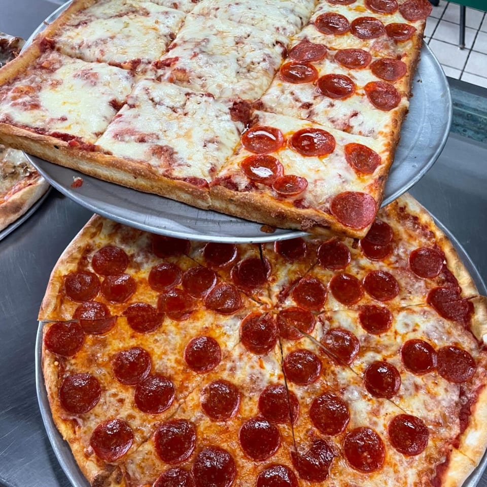 Two pizzas on metal trays, one square with cheese and pepperoni, the other round with pepperoni.